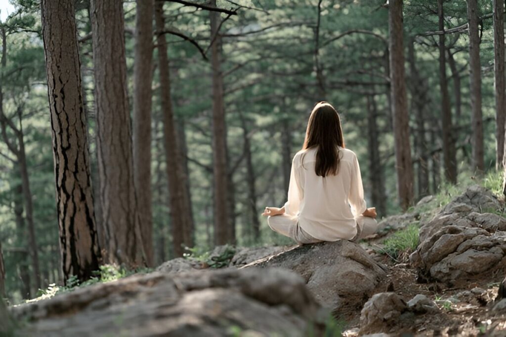 Beautiful young woman with long brunette hair meditates in nature, in a beautiful forest