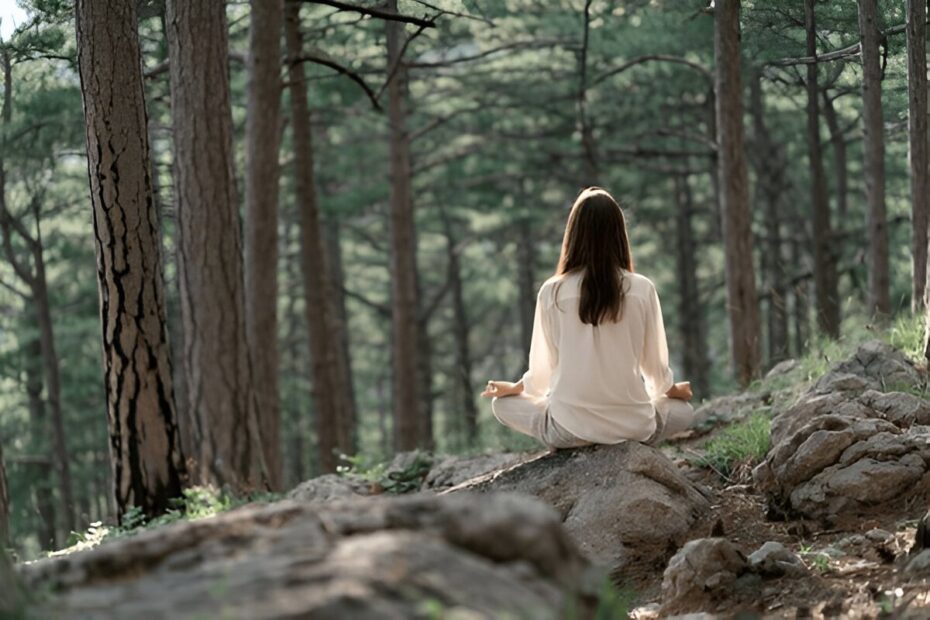 Beautiful young woman with long brunette hair meditates in nature, in a beautiful forest