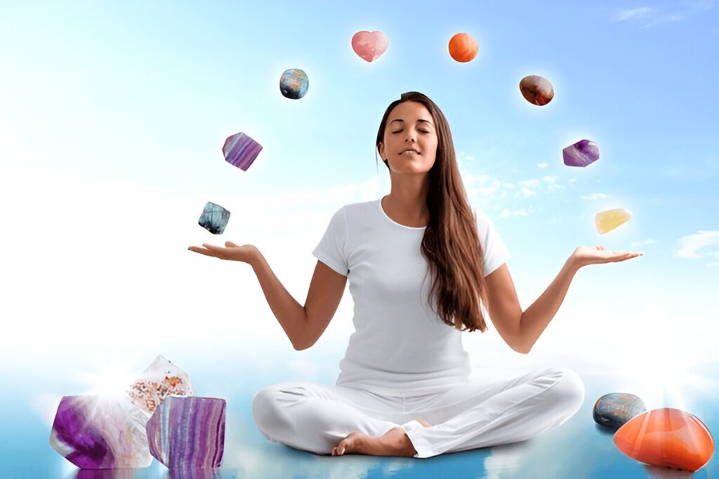 Full length portrait of young woman dressed in white doing yoga with precious gemstones