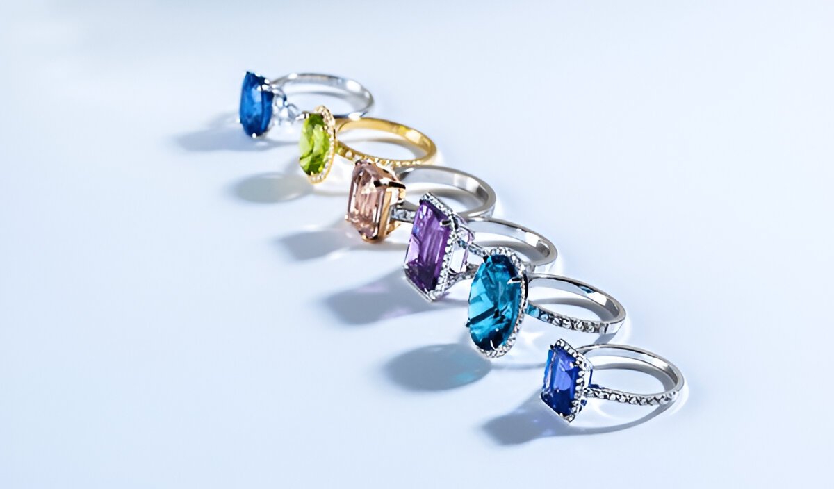 Six rings with various bright gemstones on white background.